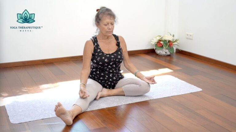 La professeure de yoga Maëva est assise en posture de l'élève et ferme les yeux, le pouce et l'index étant joints en Gyan Mudra.