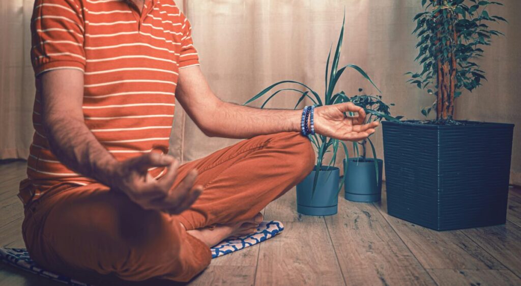 Homme assis en tailleur à côté de plantes