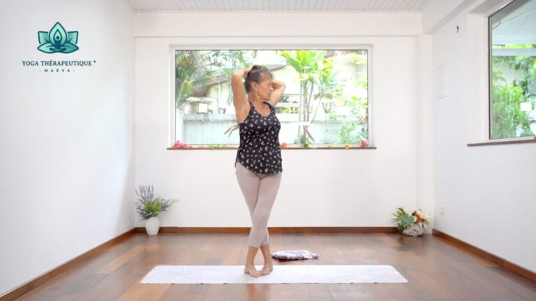 Posture de yoga : Une femme croise les jambes, les mains derrière la nuque et fait une torsion debout