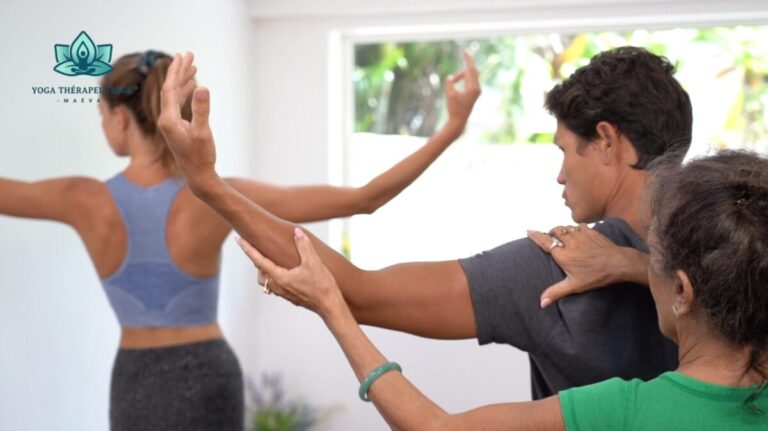 De dos, une yogathérapeute rectifie la position du bras d'un pratiquant.